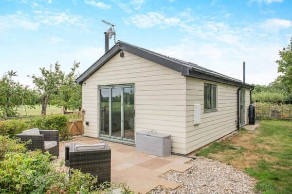 Single-story beige house with sliding glass doors opening to a stone patio and outdoor seating.