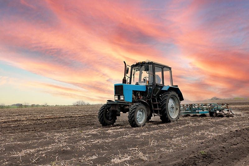 Tractor Working Under A Red Sky
